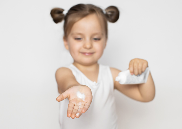 Enfant montre une crème à la texture douce et légère.